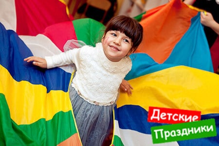 весёлая девочка играет с разноцветным парашютом